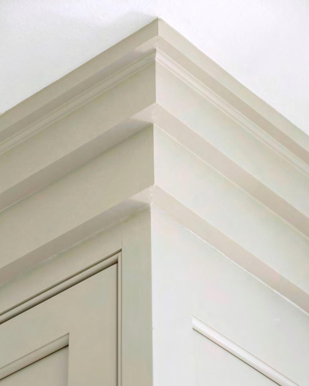 White crown molding and decorative architectural trim on top of kitchen cabinetry.