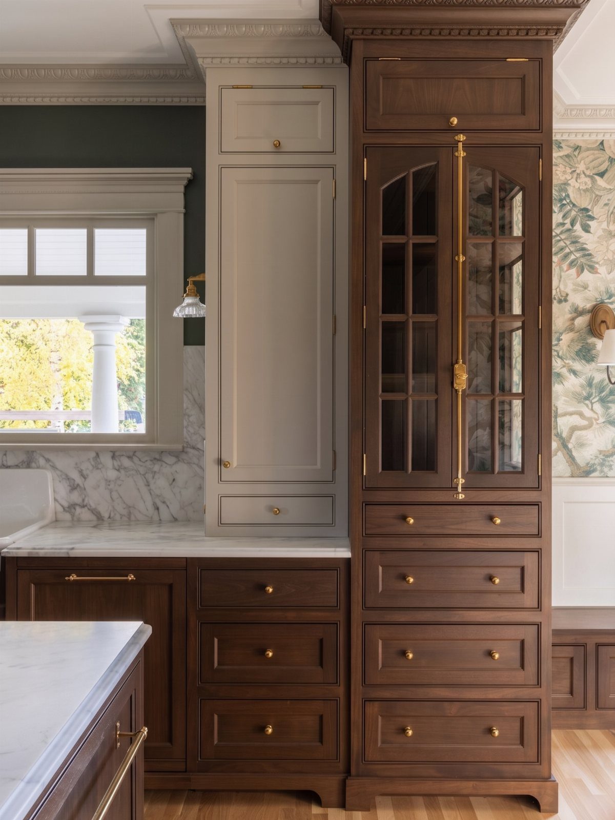 Traditional kitchen cabinetry in dark wood and cream with white marble countertops.