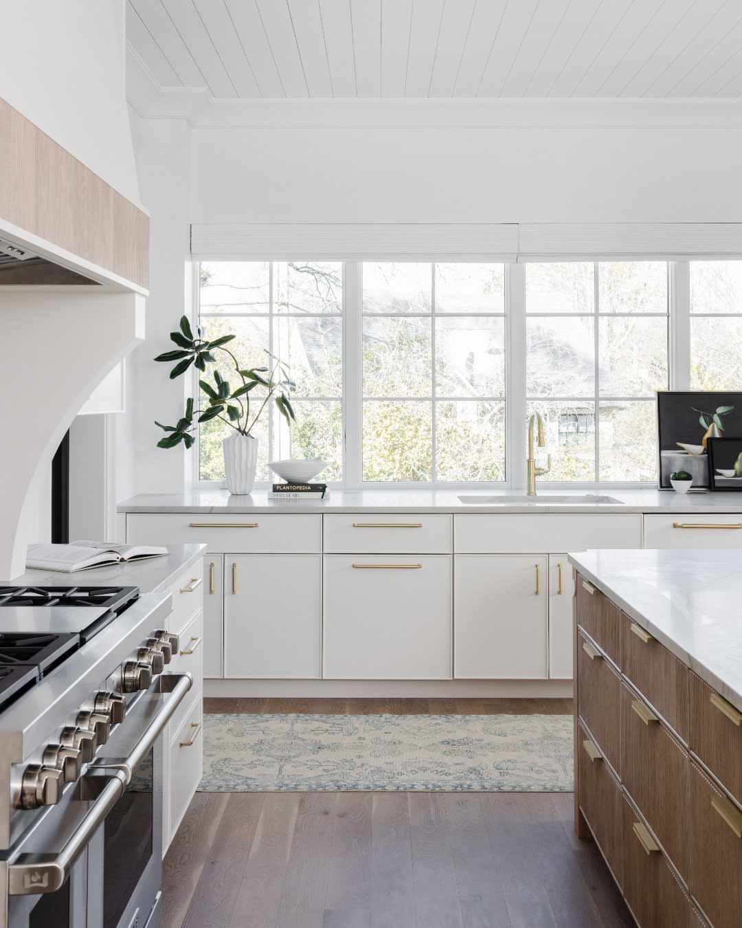 White stone countertops in a bright kitchen with white cabinets and wooden island.