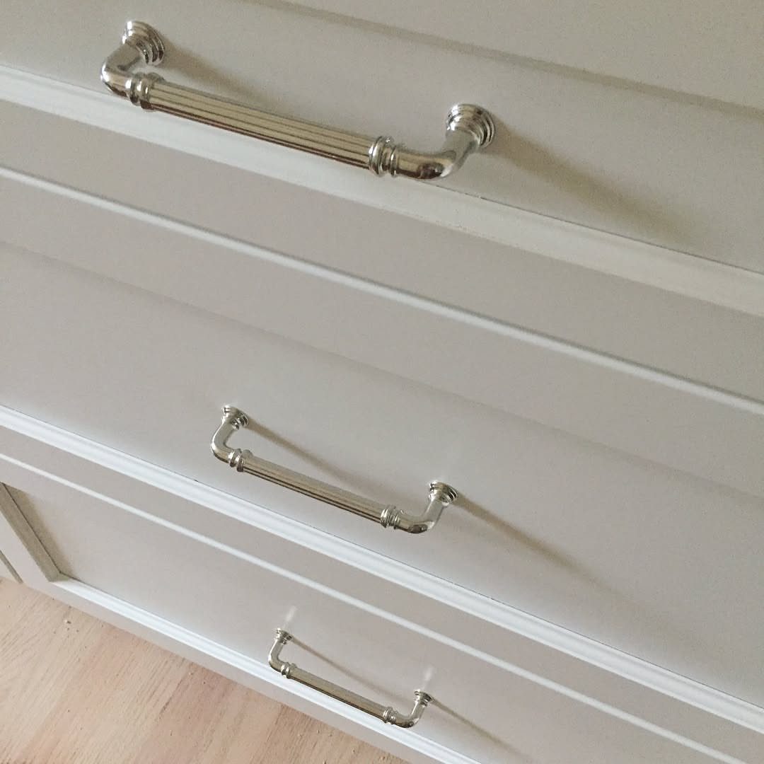 Polished nickel drawer pulls on cream colored traditional kitchen cabinetry drawers.