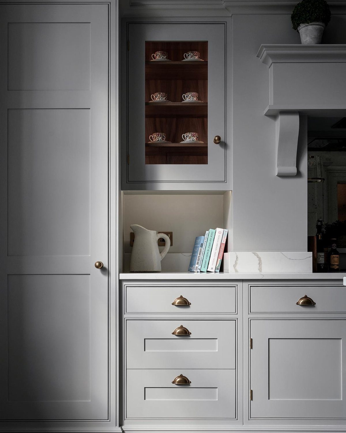 Grey shaker cabinetry with recessed panels, marble countertops, and brass hardware in a kitchen.