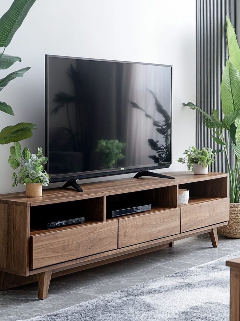 Wooden mid-century modern console table used as a TV stand with potted plants.
