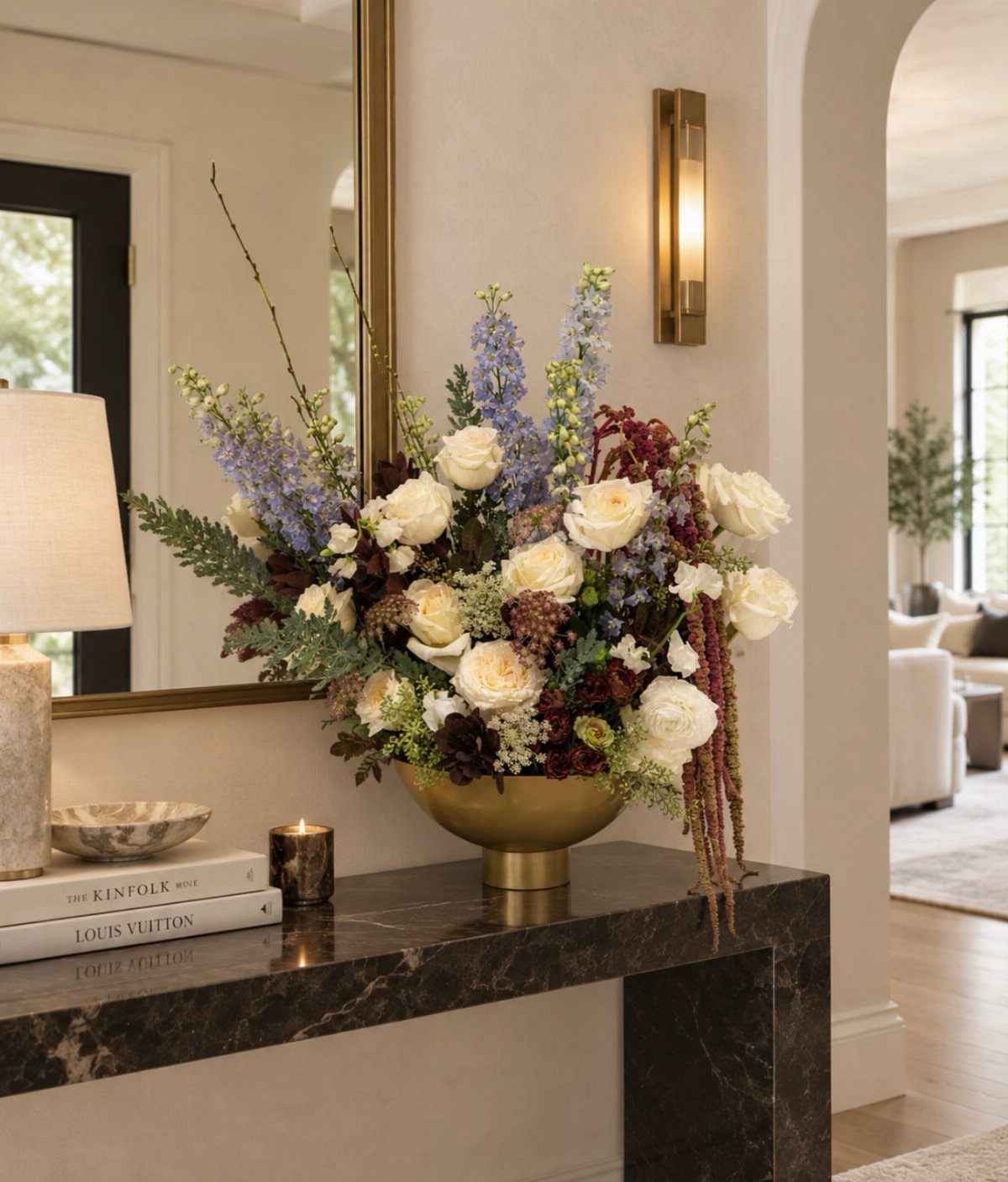 Large floral arrangement with white roses in a gold bowl on a marble console.