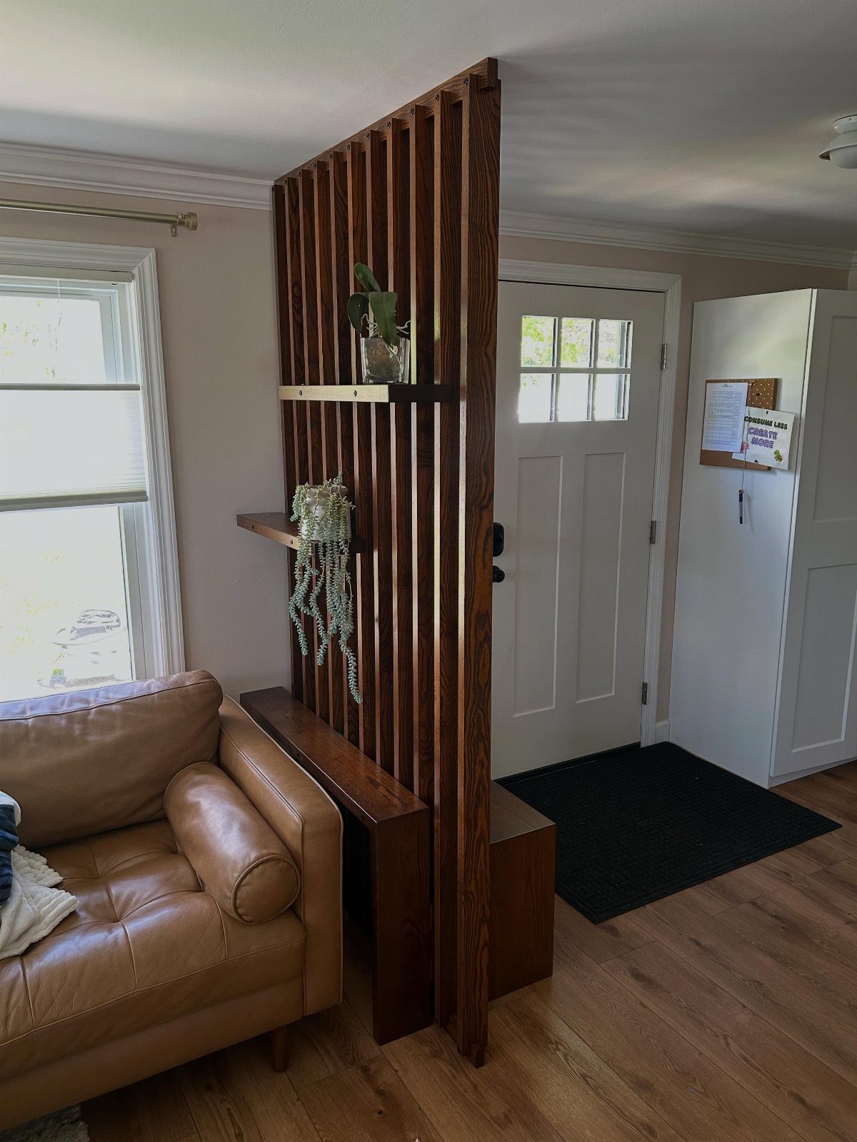 Wooden slat room divider with integrated console table next to a leather sofa.