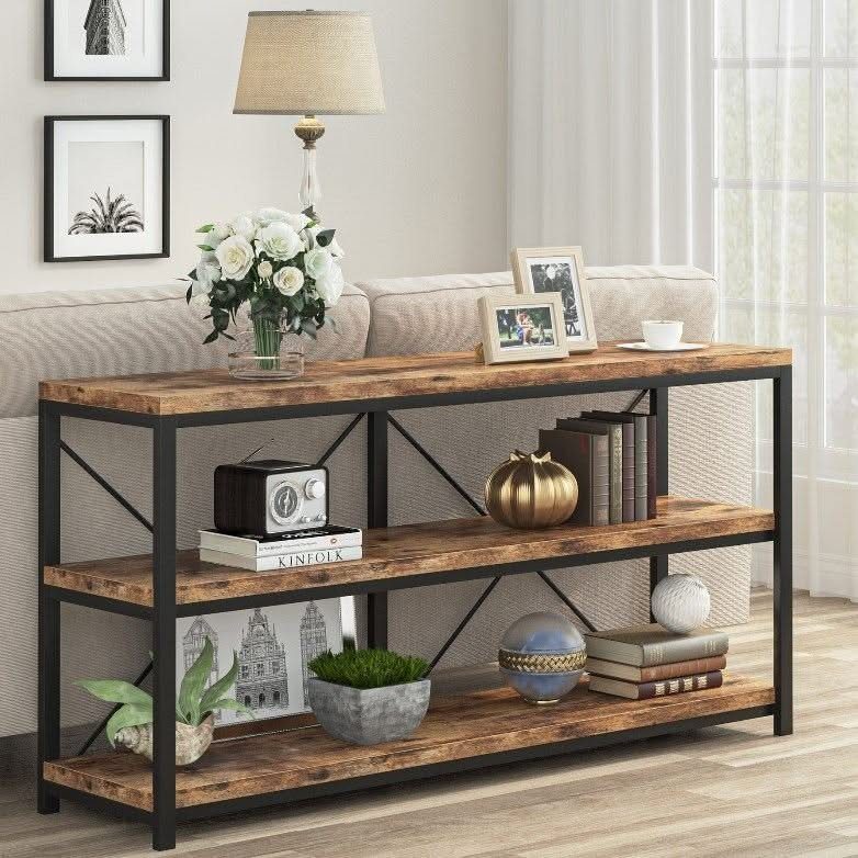 Rustic wood console table with black X-frame legs positioned behind a beige sofa.