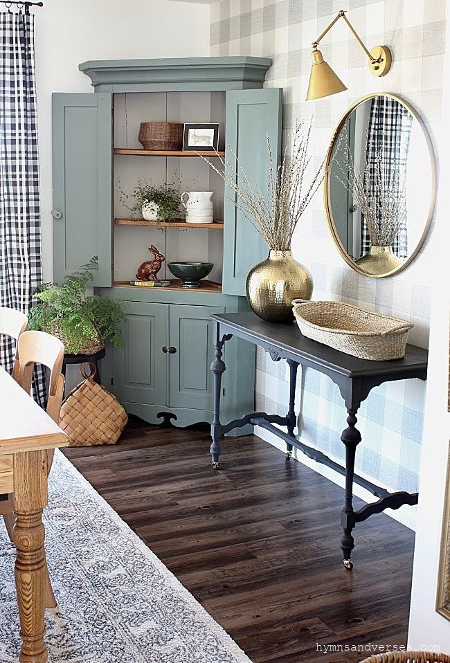 Sage green corner cabinet with a contrasting light beige interior and decorative ceramics.