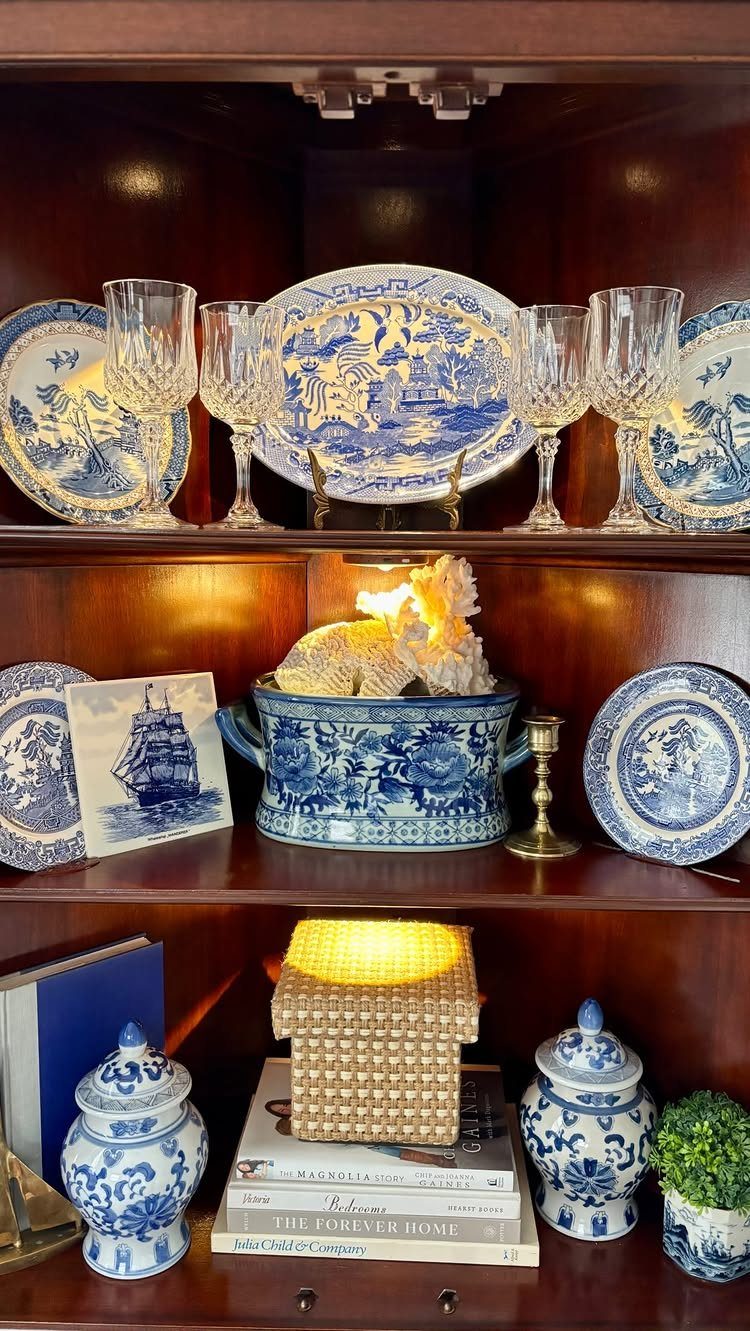 Dark wood corner cabinet displaying blue and white porcelain and crystal glassware.