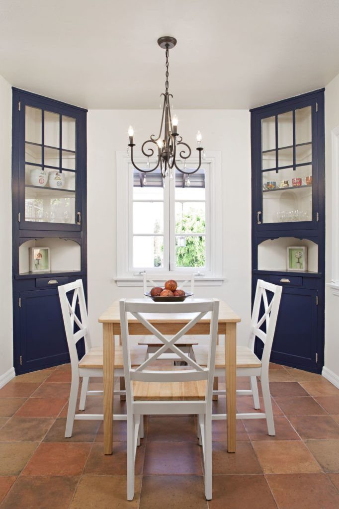 Navy blue cabinets flanking a window in a dining room with white chairs.
