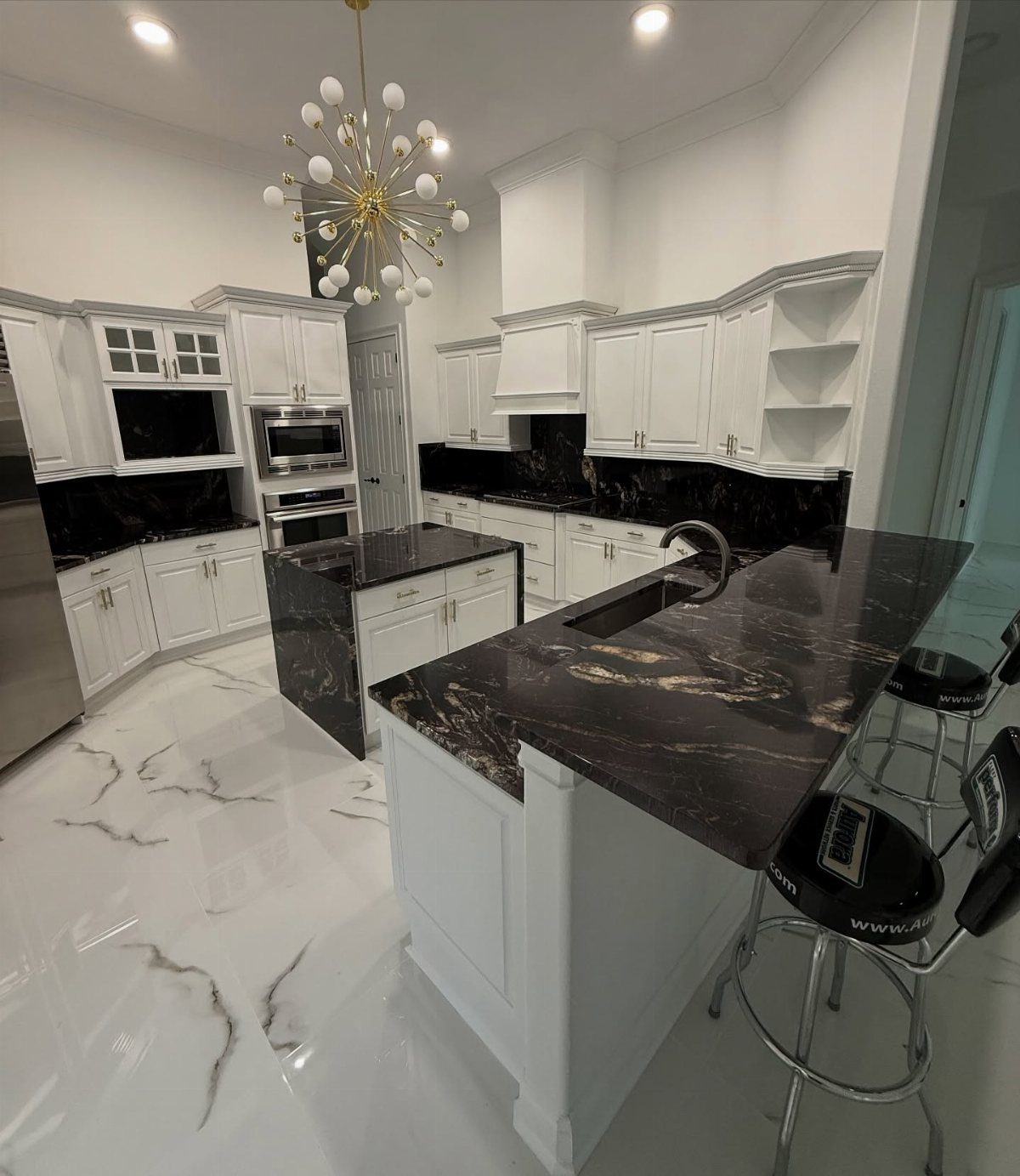 White kitchen with dark black marble countertops and white marble floors