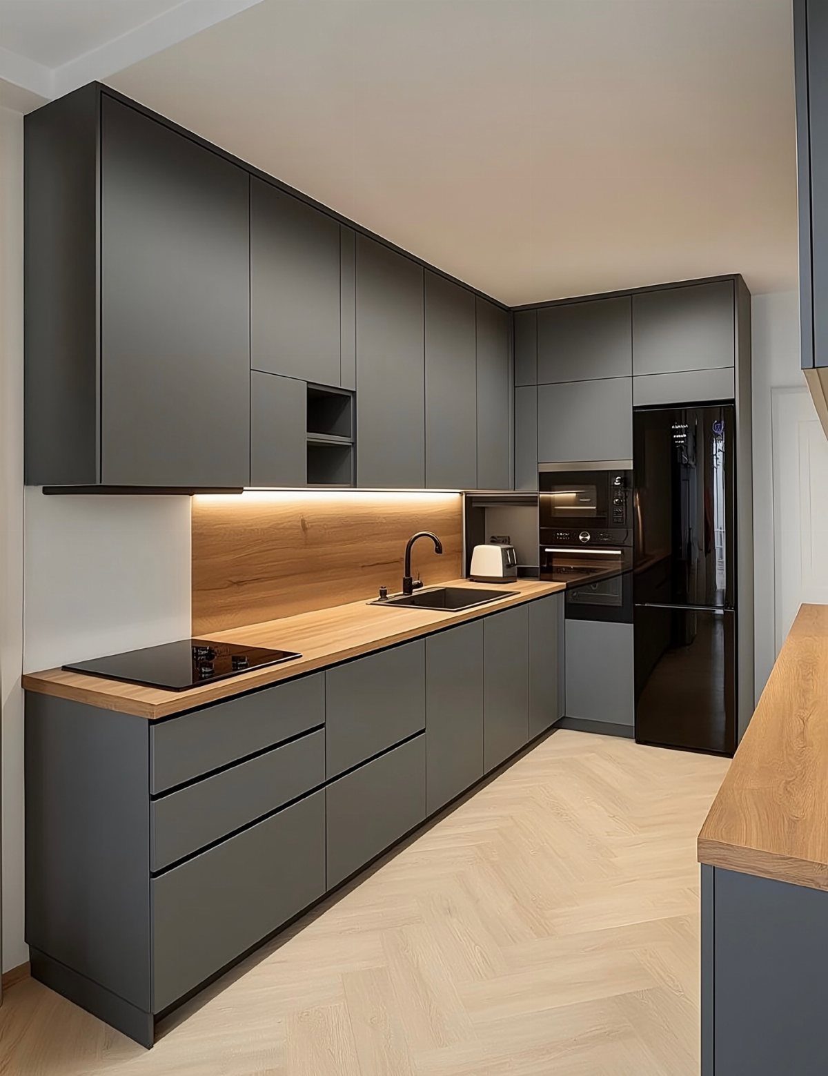 Dark grey matte kitchen cabinets with light wood countertops and herringbone wood flooring.