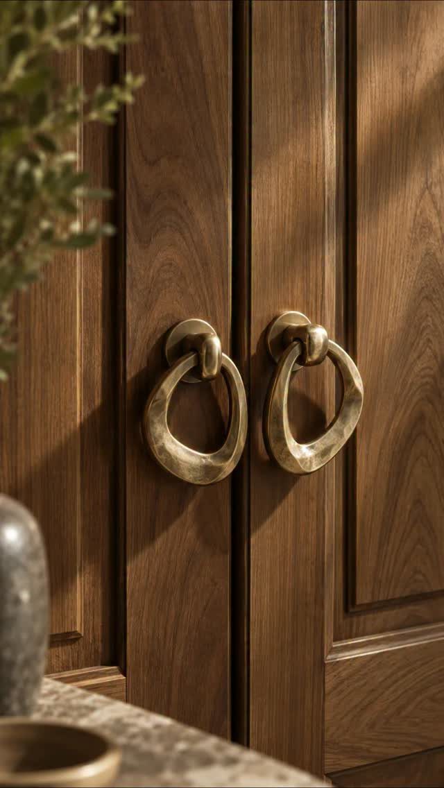 Dark brown wood kitchen cabinets with large circular brass ring handles.