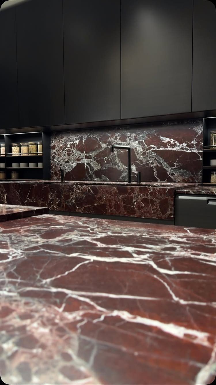 Matte black kitchen cabinets paired with bold red and white veined marble countertops.