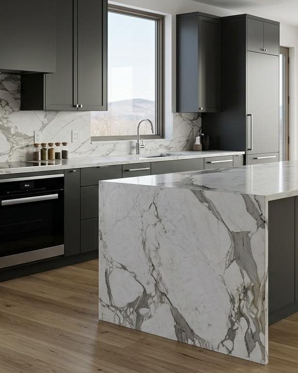 Modern kitchen with dark grey cabinets and white marble countertops and island.