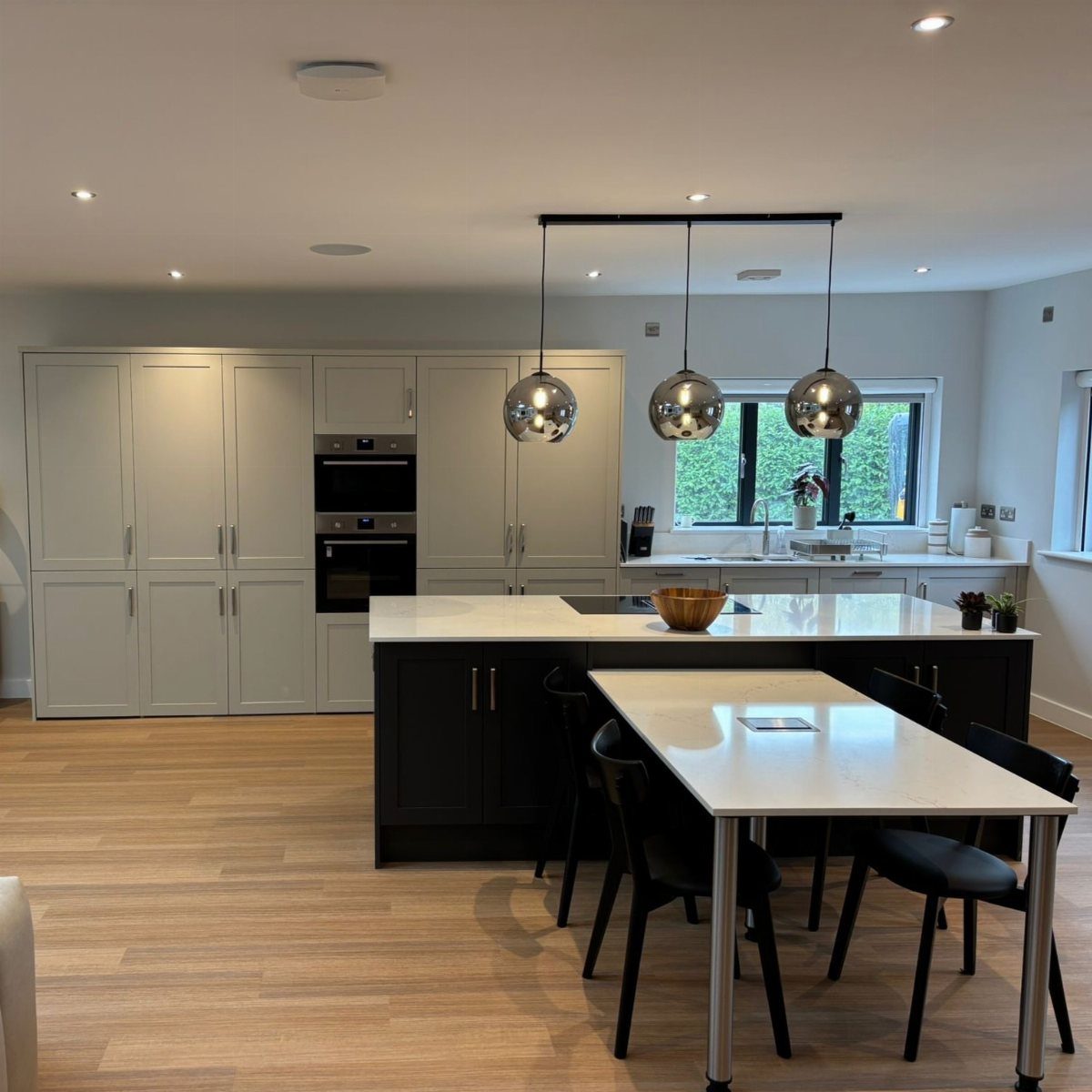 Modern kitchen with light grey cabinets, dark charcoal island, and white countertops.