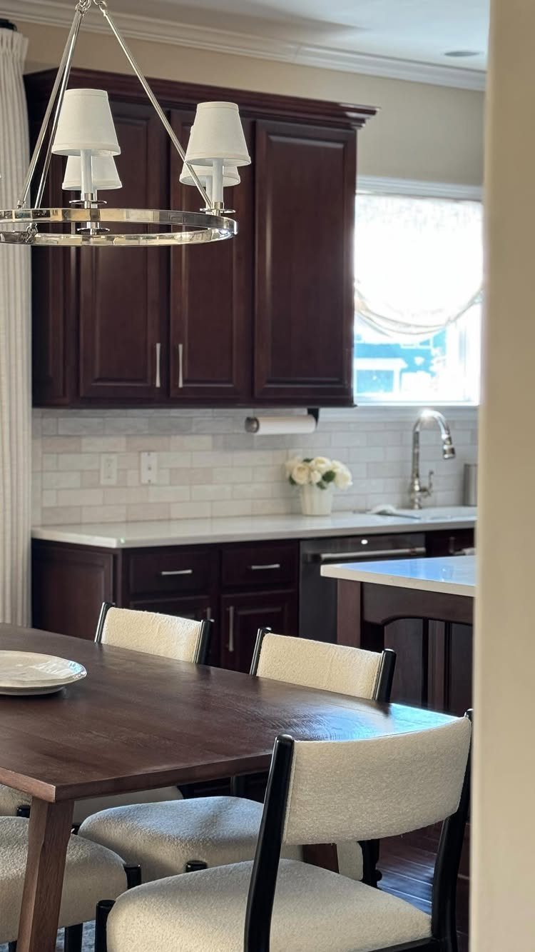 Dark brown wooden kitchen cabinets with white countertops and a matching dining set.