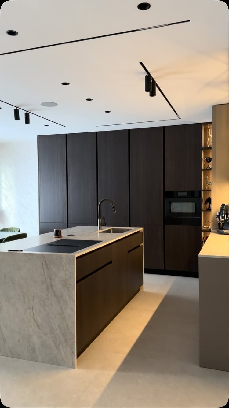 Modern kitchen with dark brown cabinets and a large marble-textured island.