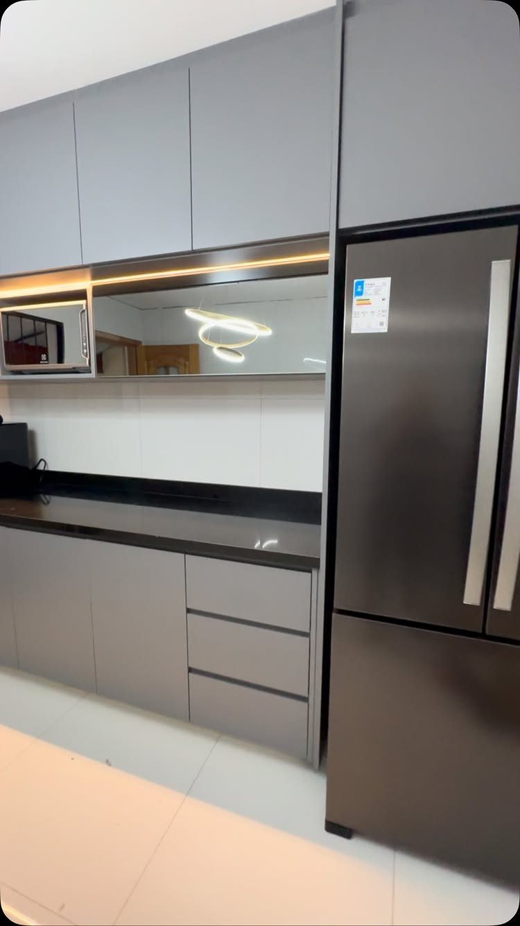 Modern kitchen with matte grey cabinets, black countertops, and a dark grey refrigerator.