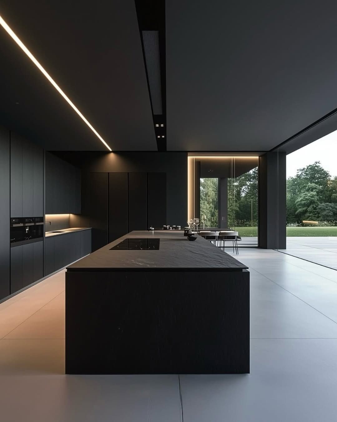 Modern minimalist kitchen with matte black cabinets, a large black island, and grey floors.