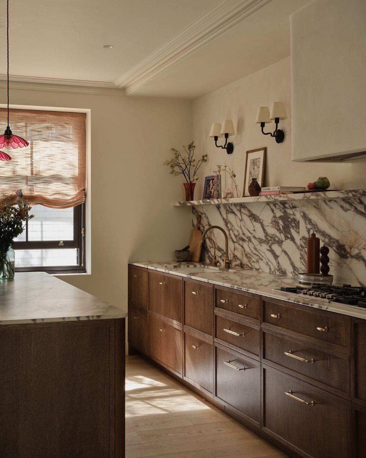 Dark brown wood cabinets with marble countertops and white walls in a kitchen.