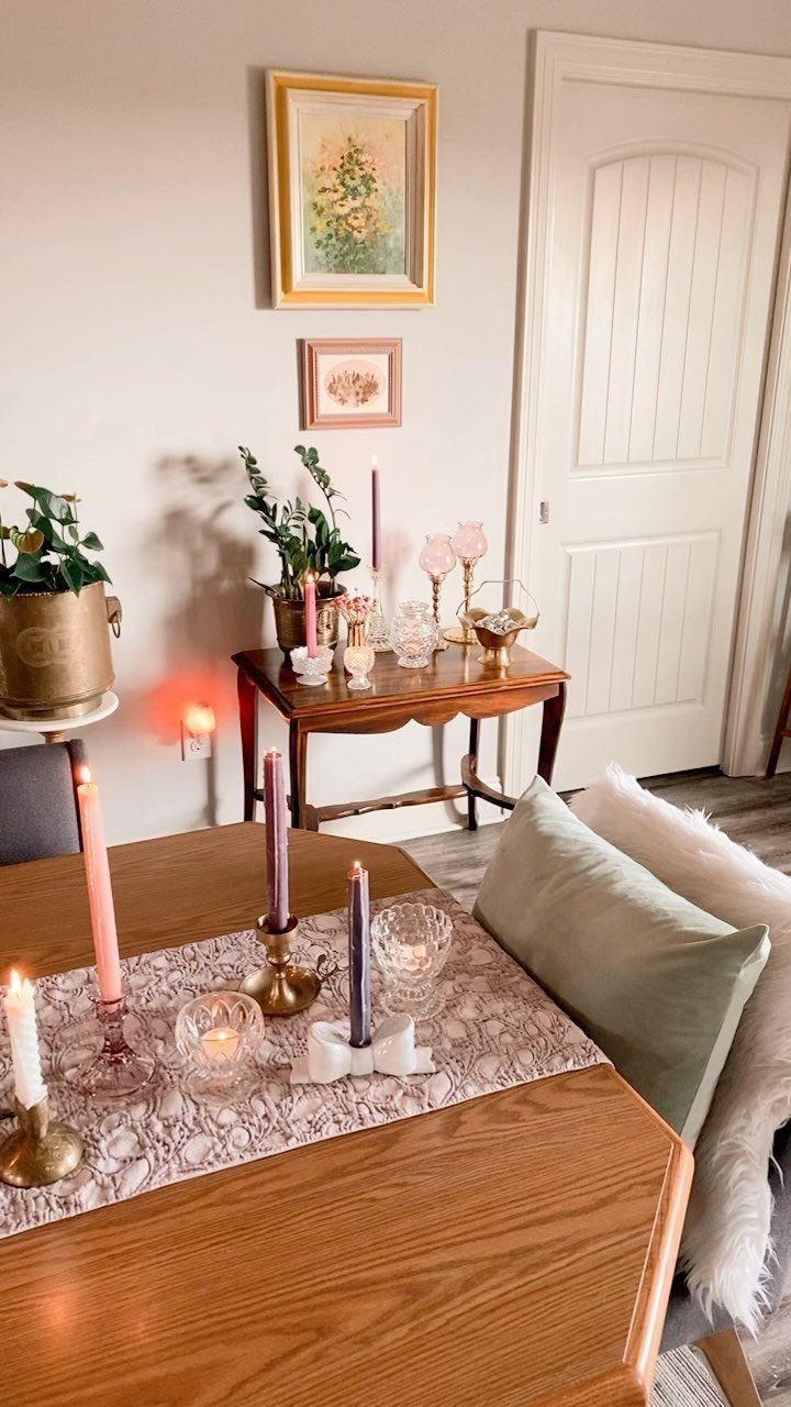 Lit taper candles in gold holders on a patterned dining table runner