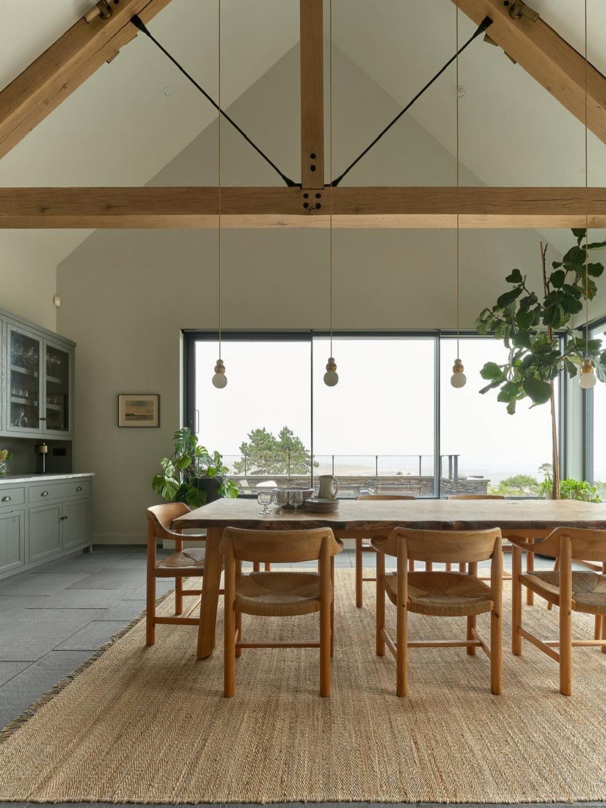 Vaulted ceiling with exposed wood beams above a rustic wooden dining set and rug.