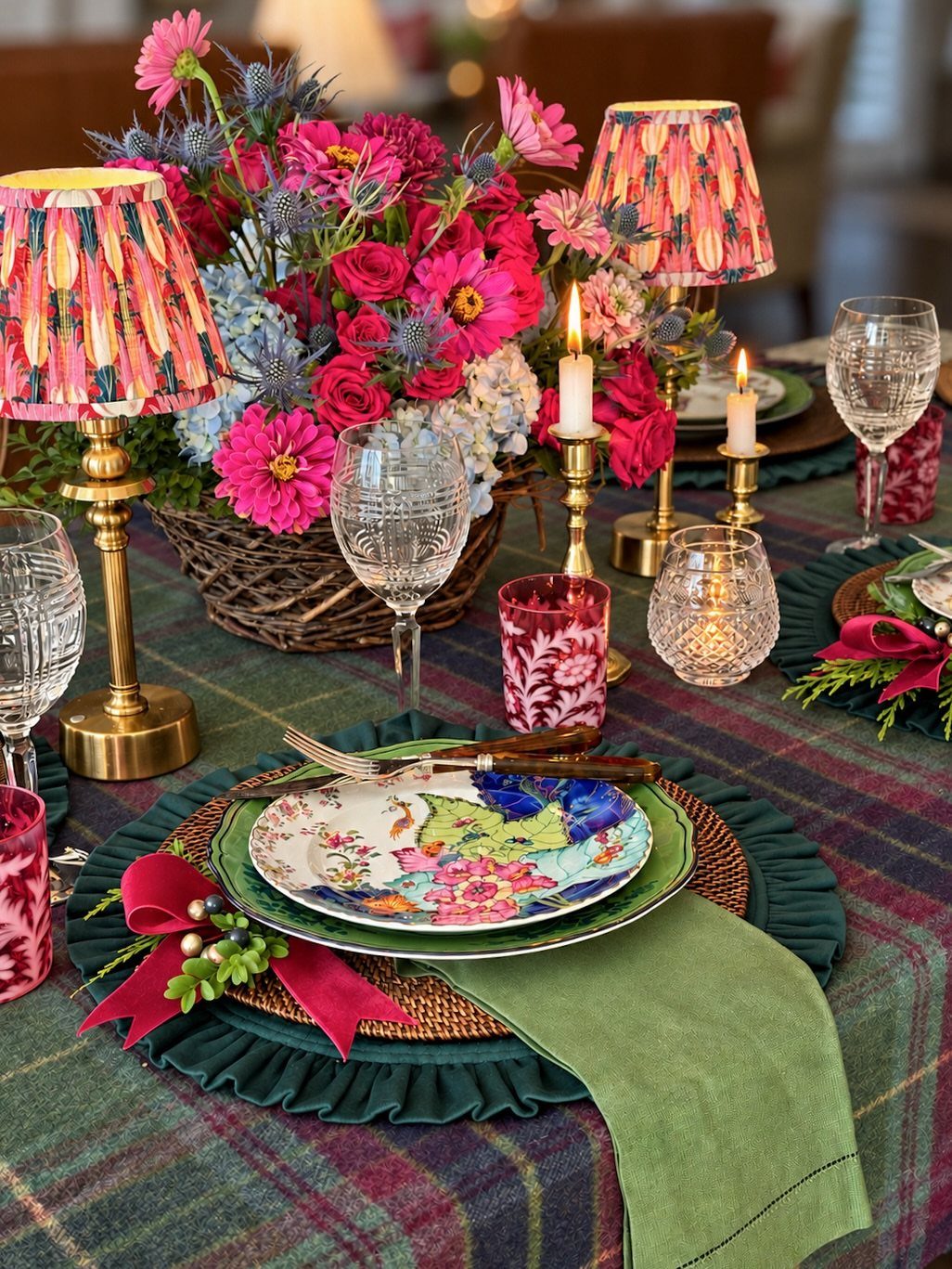Dining table set with plaid tablecloth, green linens, floral plates, and colorful flowers.