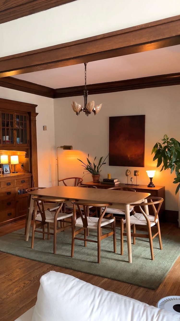 Light wood dining table and chairs placed on a muted green area rug.