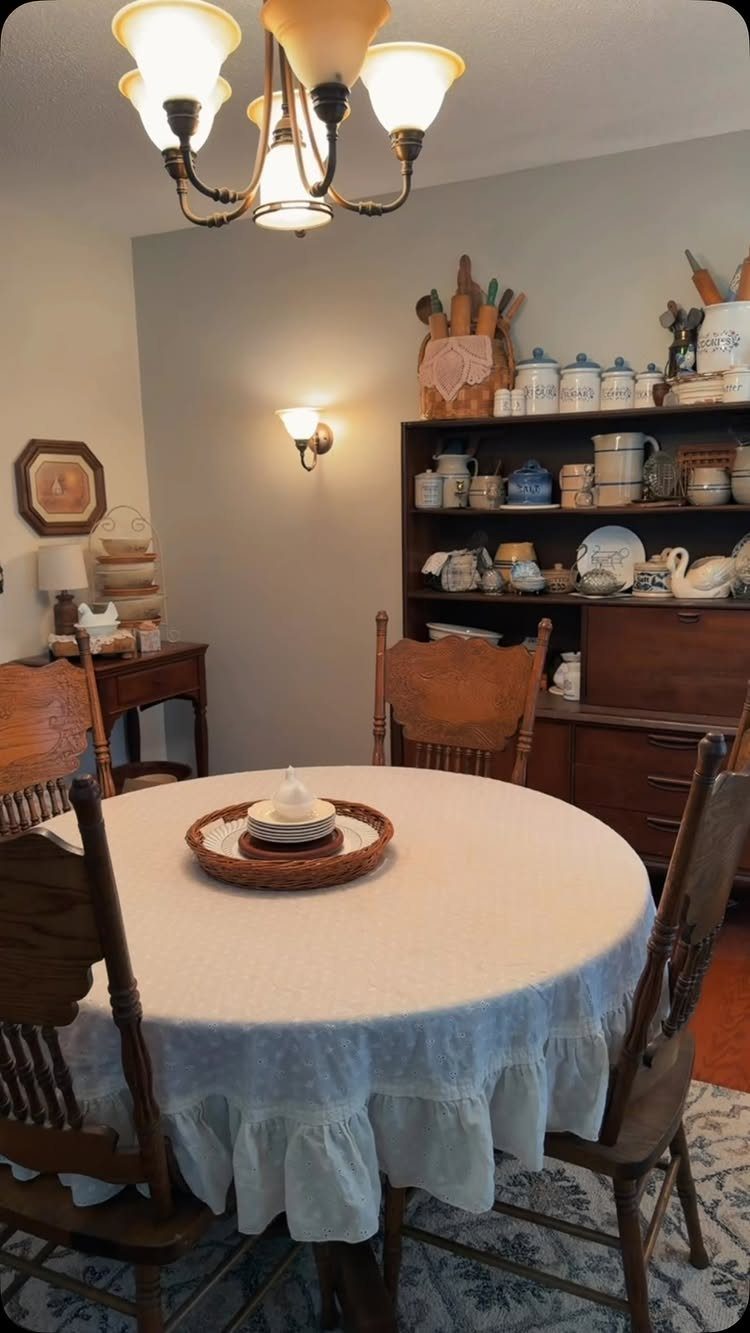 Cottage dining room with a round table and a hutch displaying vintage dishes.