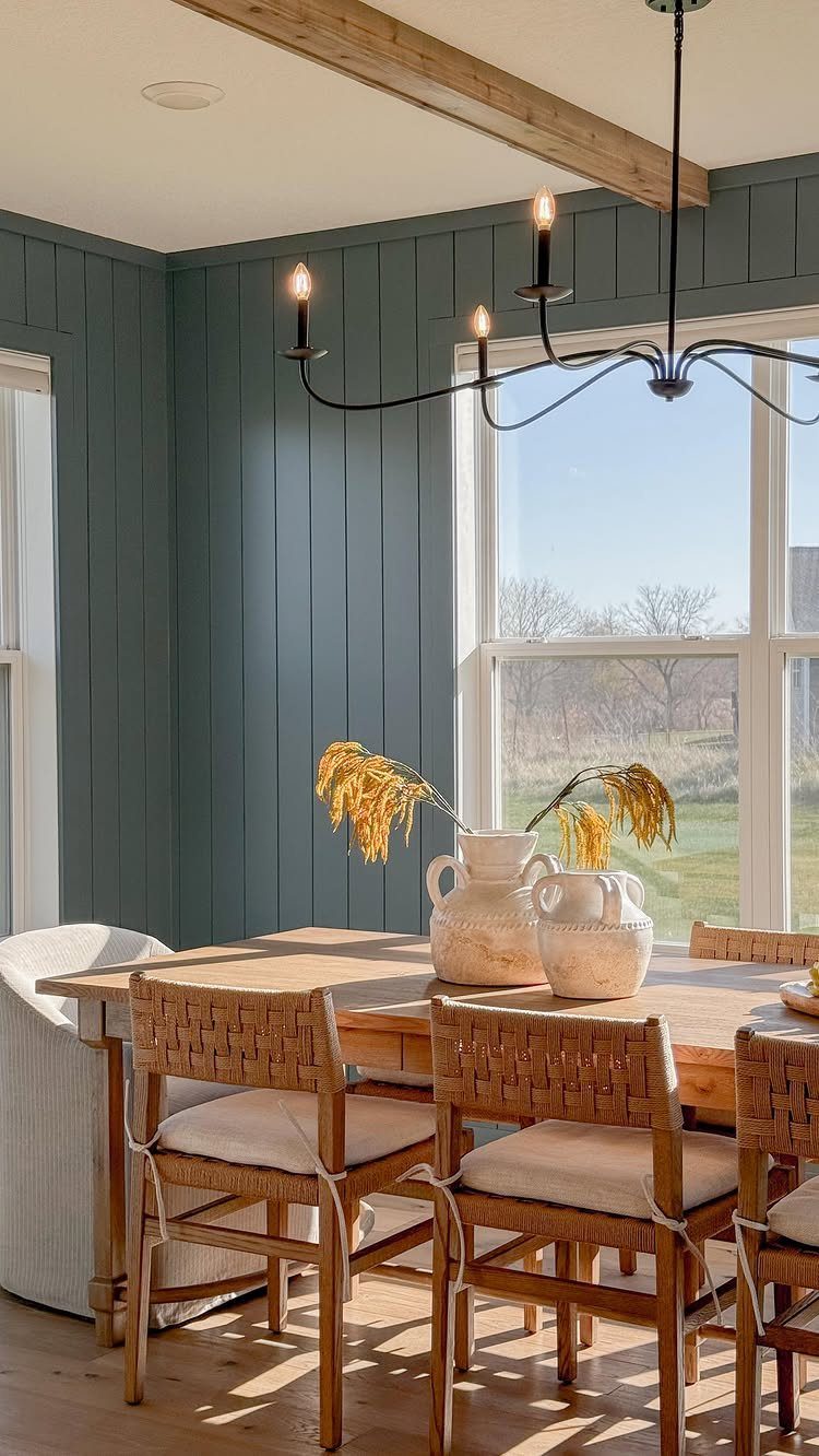 Country dining room with wooden table, woven chairs, and blue-grey paneled walls.