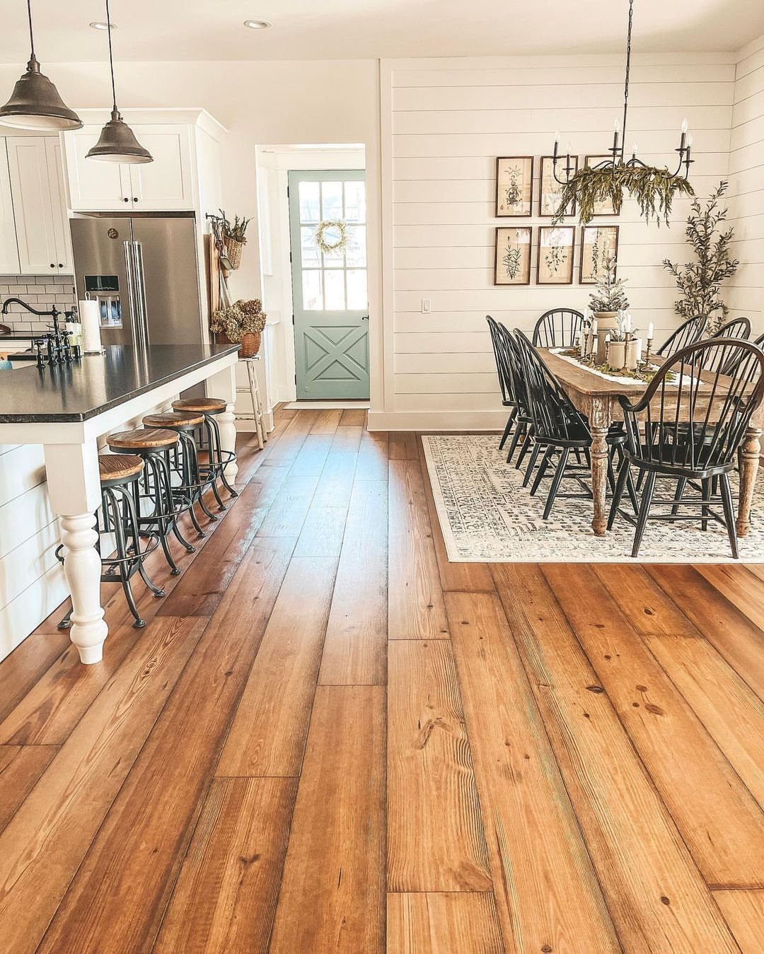Dining room with wide wooden floors and a white shiplap accent wall.