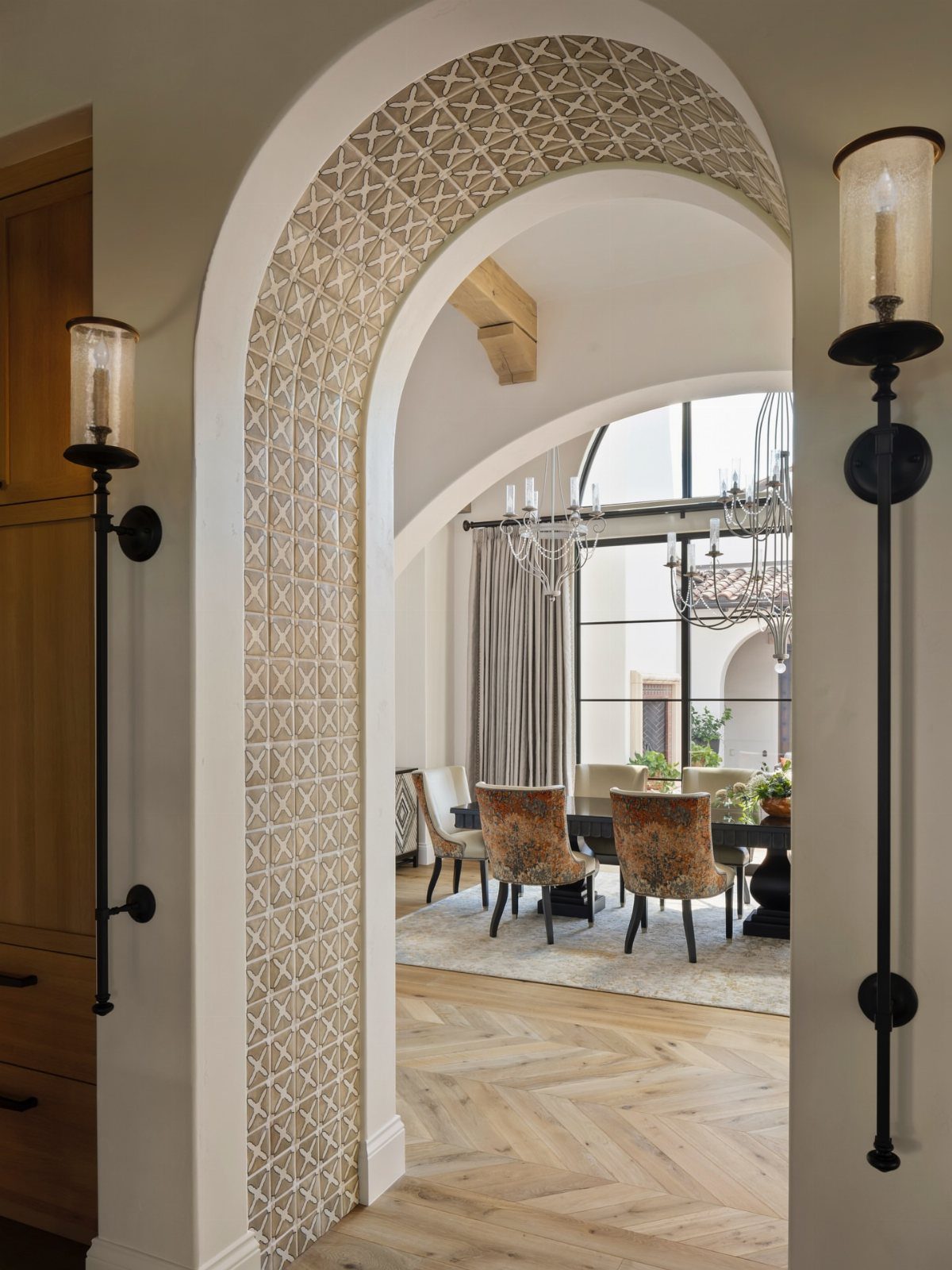 Light-colored herringbone wooden floors in a dining room viewed through an arched doorway.