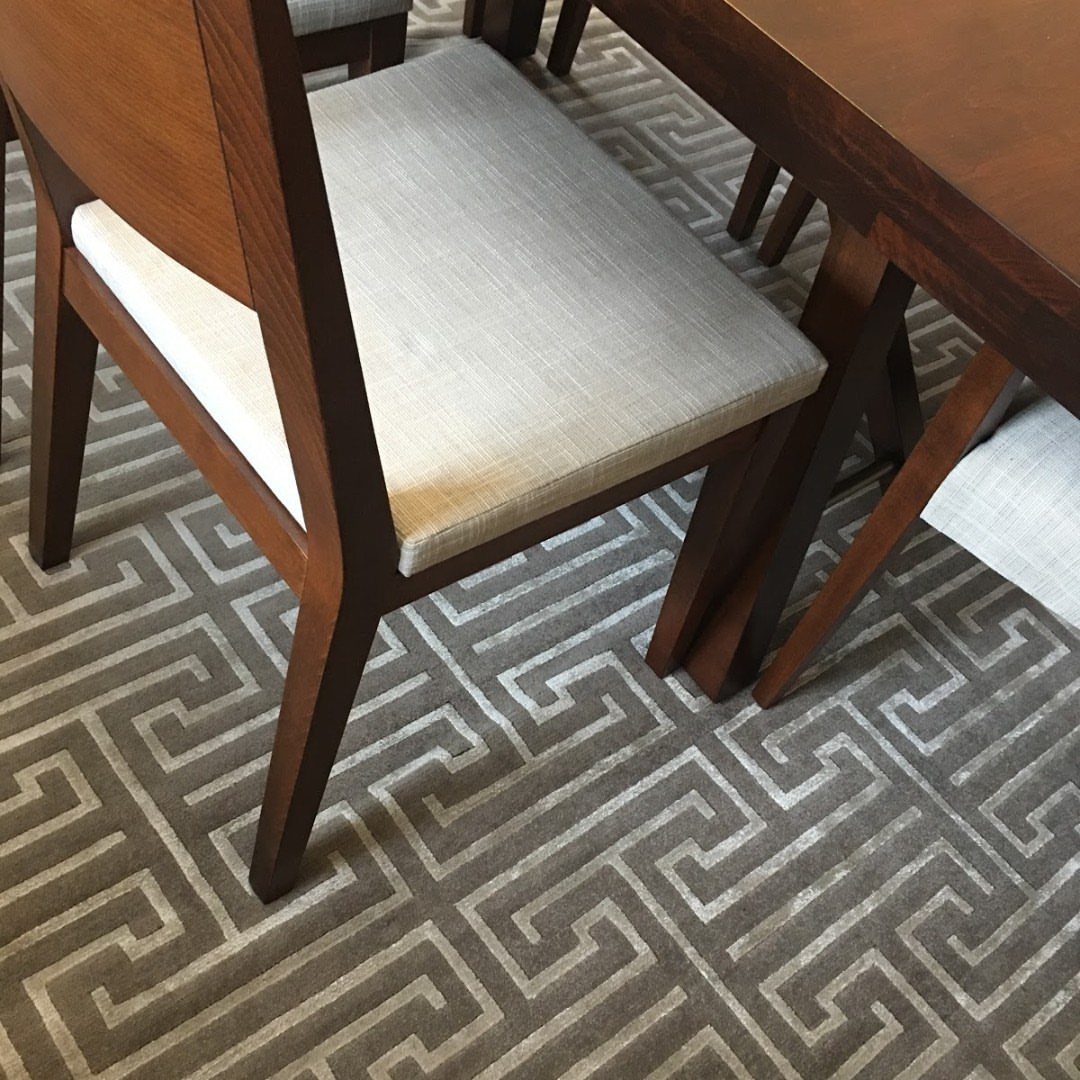 Wooden dining chair and table leg on a gray geometric patterned rug