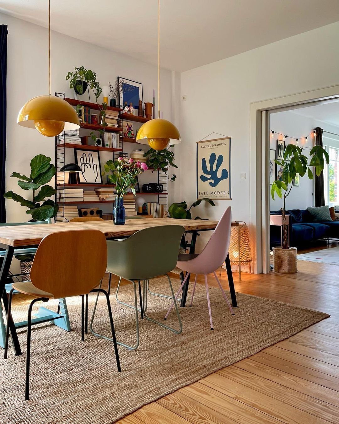 Modern dining room with mismatched colorful chairs on a natural jute area rug.
