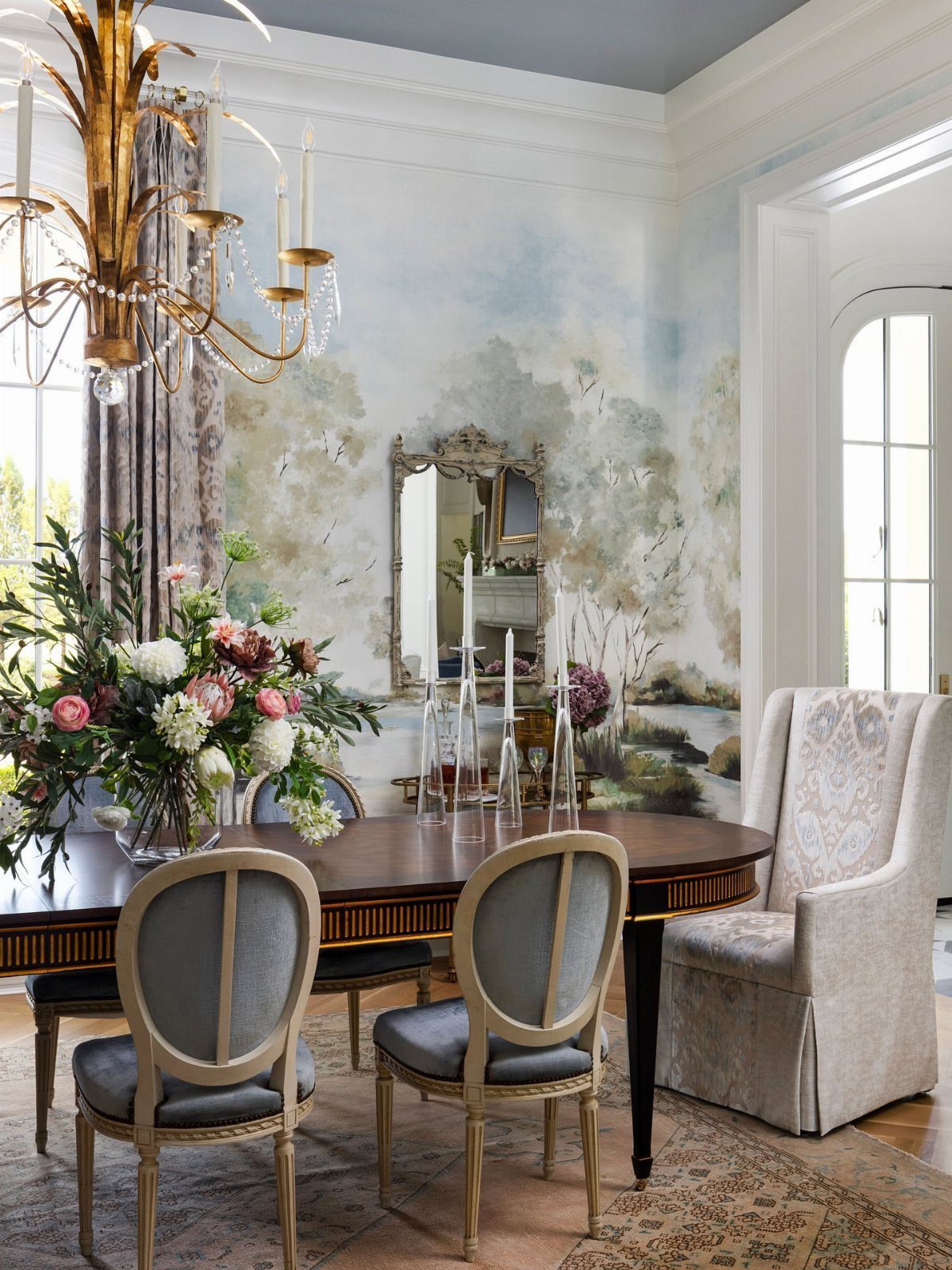 Oval wooden dining table with grey chairs on a patterned beige area rug.