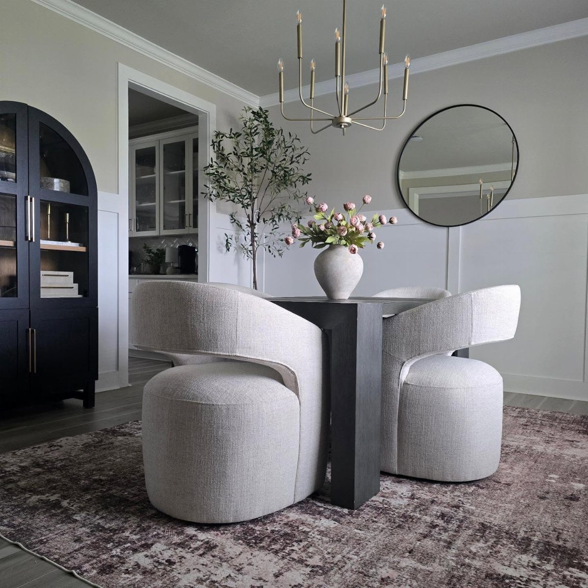 Low-pile patterned rug under a dark dining table with curved gray chairs.