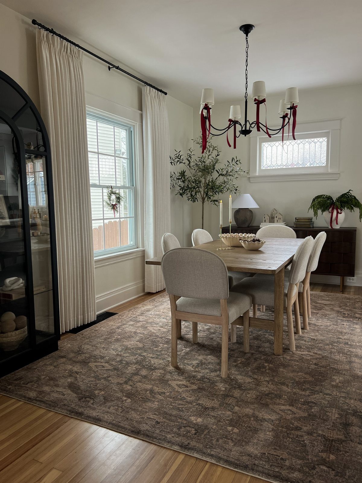 Dining room with wooden table, chairs, and a sideboard featuring a white lamp.