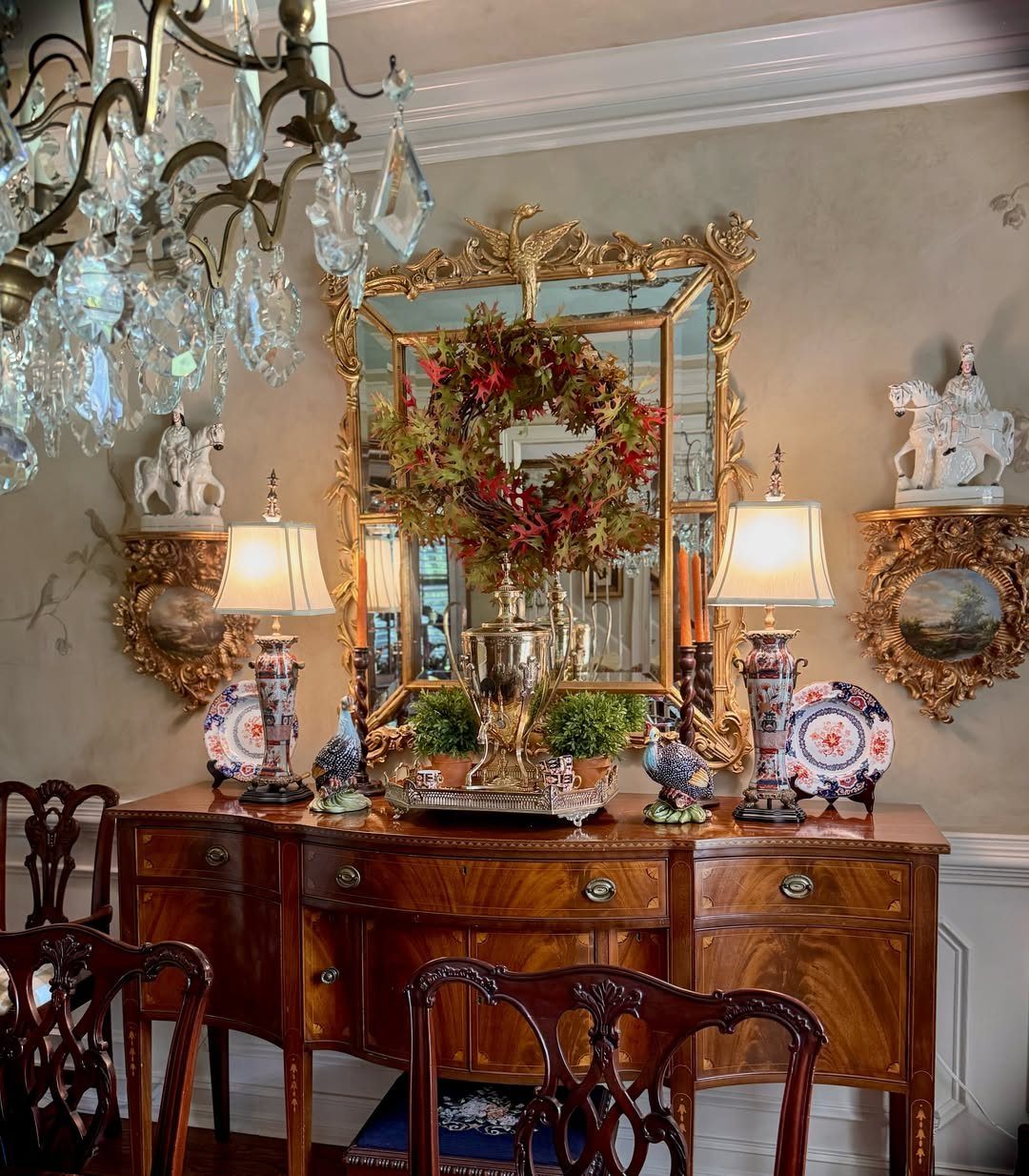 Symmetrical sideboard styling with matching lamps and plates under a large gold mirror