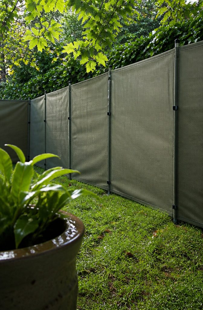 Sage fabric fence on portable posts behind a rain-speckled ceramic planter