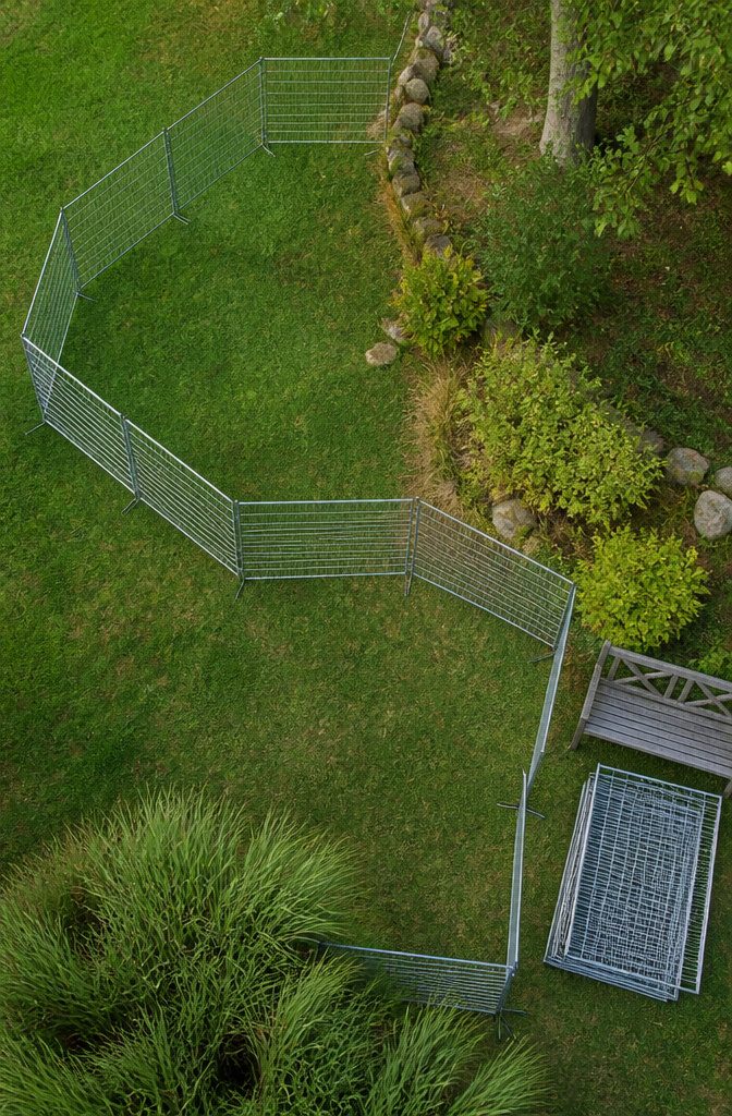 Portable fence panels joined into an enclosure with ground anchors