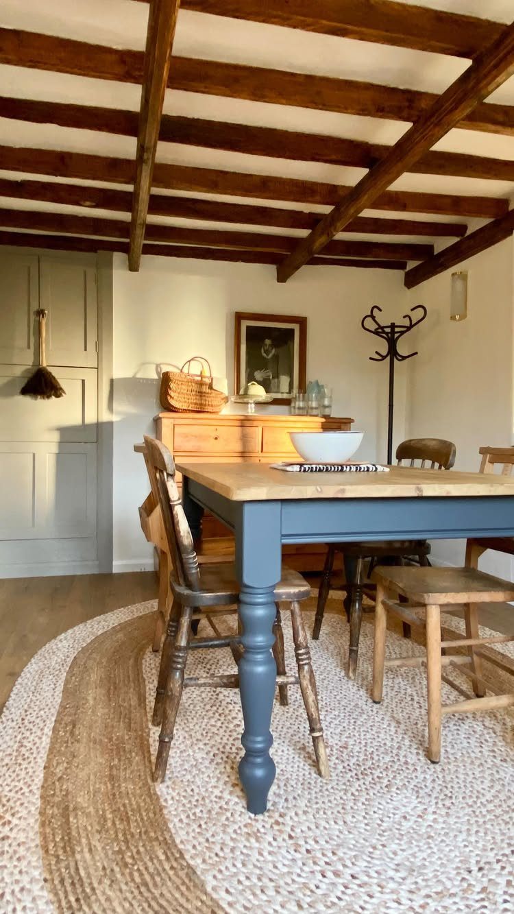 Blue and wood farmhouse dining table with matching chairs on a woven rug.