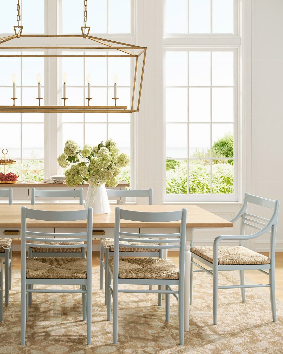 Light wood dining table with light blue woven chairs in a bright room.