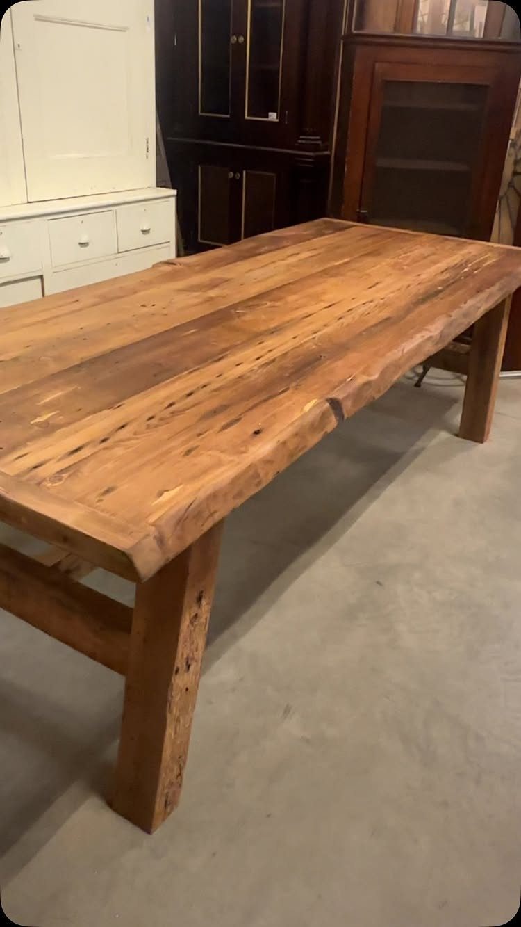Rustic wooden farm table with a thick top and heavy block legs.