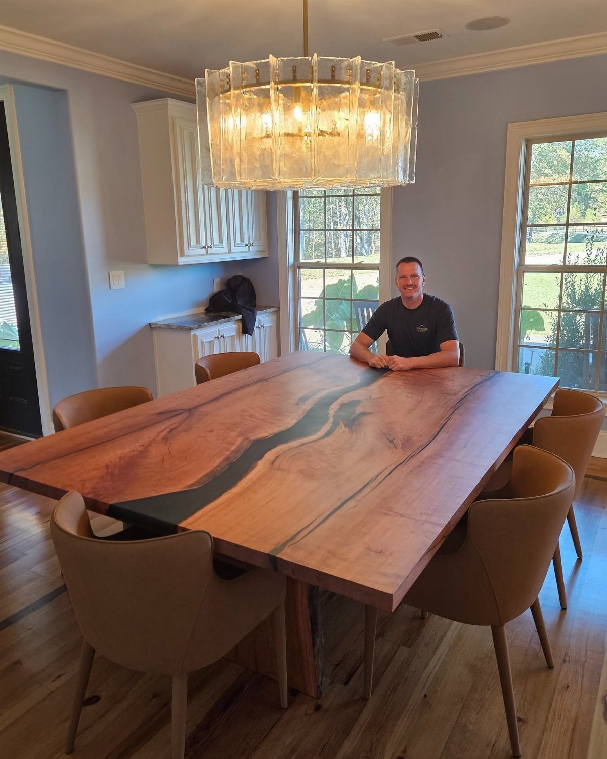 Live-edge wooden dining table with resin river and tan leather chairs in dining room.