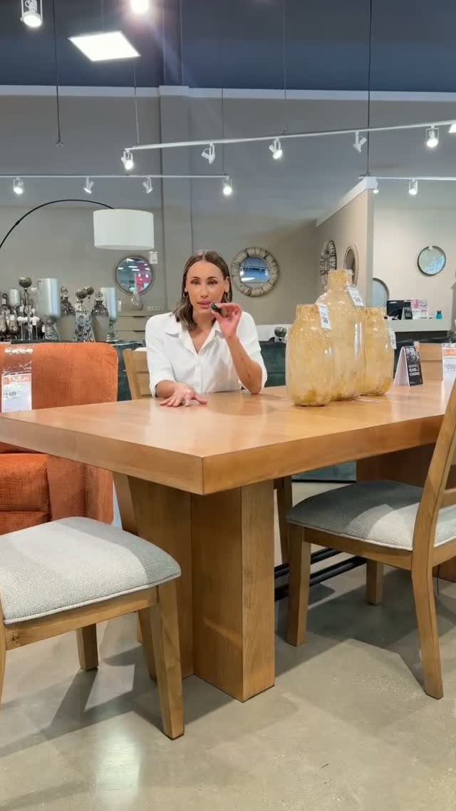 Upholstered dining chairs and a wooden table in a bright furniture store showroom.