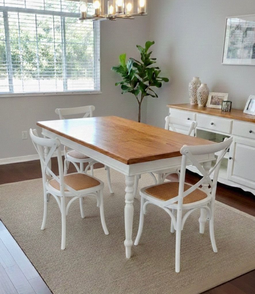 White and wood dining table with matching cross-back chairs on a neutral rug.