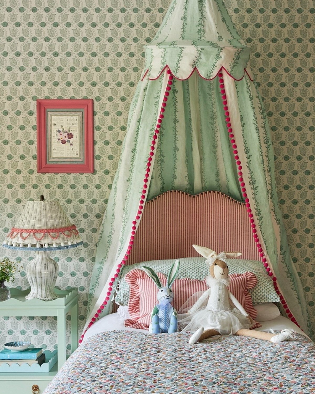 Bed with a green striped canopy, pink scalloped headboard, and floral bedding.