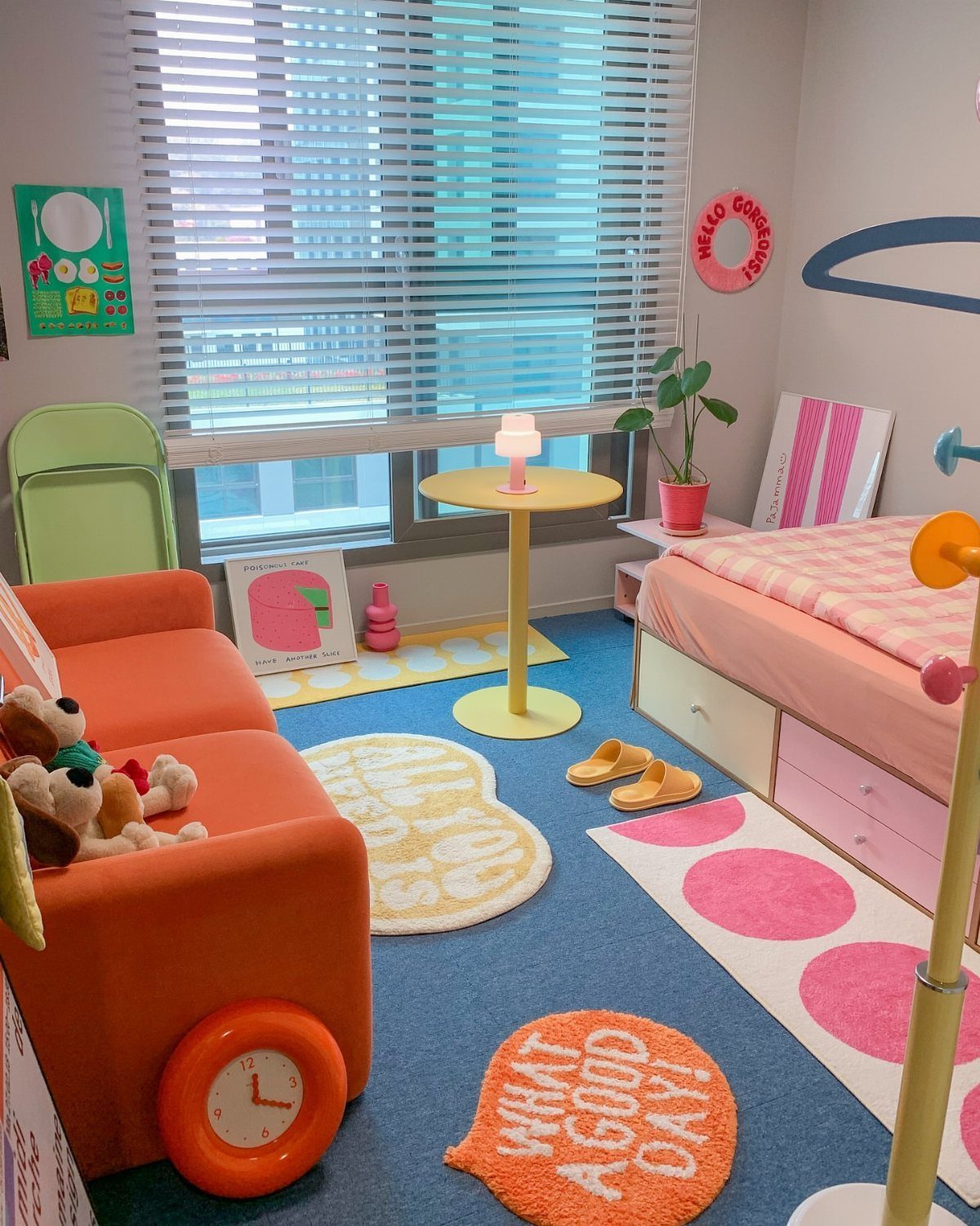 Colorful girl's bedroom with pink bed, orange armchair, and bright patterned rugs.