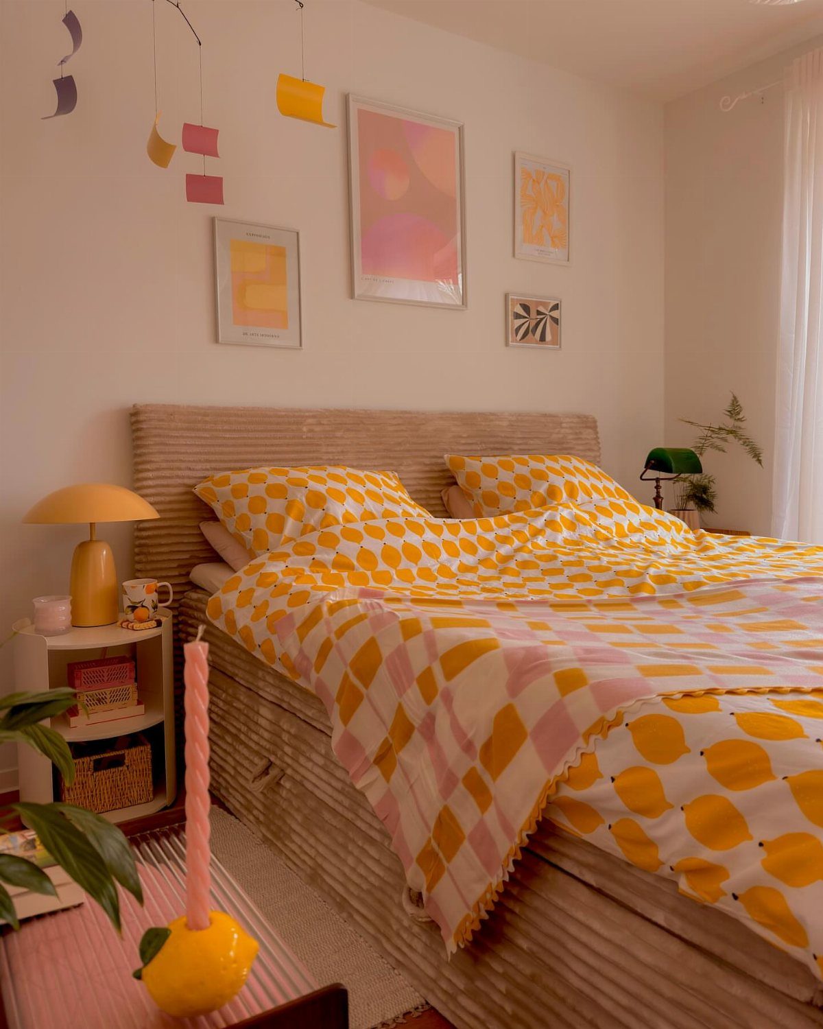 Bed with mustard-yellow bedding and salmon-pink abstract art on a white wall.
