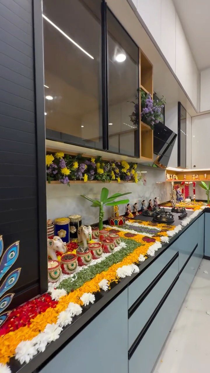 Modern kitchen counter decorated with colorful flower petals and traditional Indian figurines.