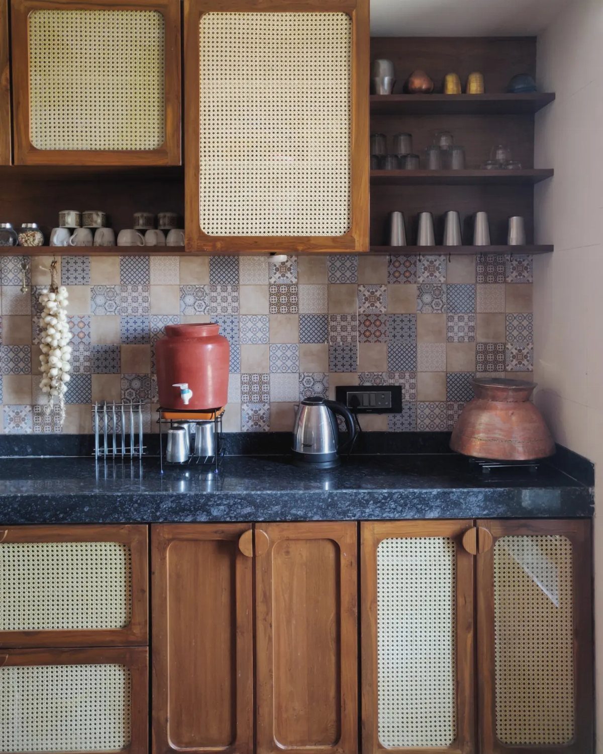 Wooden kitchen cabinets with woven cane panels and patterned tile backsplash.